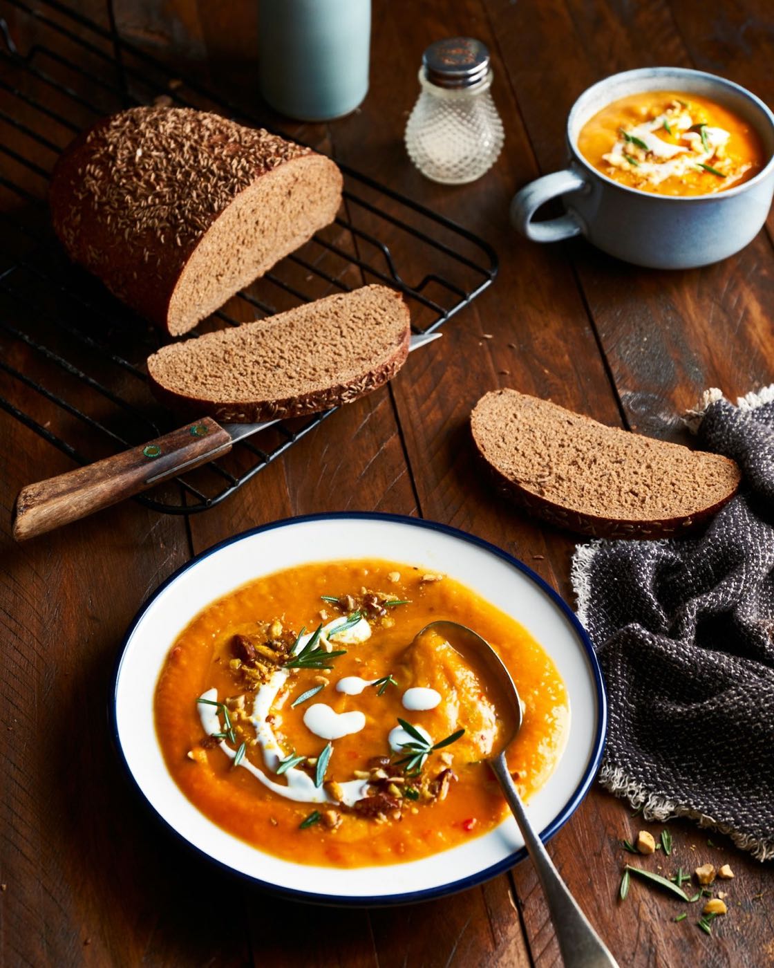Bowl of golden squash soup with fresh bread on a wooden table